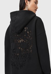 Felpa nera con cappuccio caratterizzata da un design a taglio testurizzato sulla schiena, che rivela uno strato a contrasto sottostante. Include un cappuccio e una vestibilità comoda.