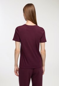 Bordowa koszulka z miękkiej bawełny, z okrągłym dekoltem i krótkimi rękawami. Prosty design bez dodatkowych wzorów czy akcentów.