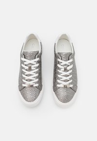 Šedé tenisky s vzorovaným povrchem, strukturovaným svrškem, bílými tkaničkami a bílou gumovou podrážkou. Na jazyku je umístěn kovový detail s logem.