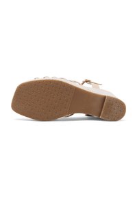 Sandalo beige con un design della tracolla testurizzato e una suola in gomma caratterizzata da un motivo a diamante, che mostra i dettagli di trazione della suola.