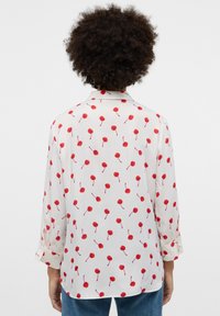 White shirt with red cherry pattern, long sleeves, button cuffs, and a collar. Soft fabric with a smooth texture. Back view shown.