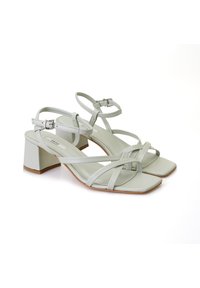 Hellgrüne Blockabsatzsandalen mit quadratischen Zehen und mehreren überkreuzten Riemen. Verstellbarer Knöchelriemen mit einer metallenen Schnalle.