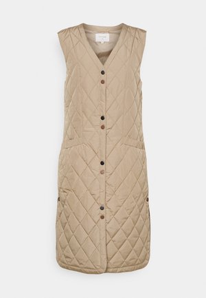 Beige mouwloze doorgestikte lange bodywarmer met V-hals, drukknoopsluiting aan de voorkant in afwisselend zwart en bruin, en zijzakken.