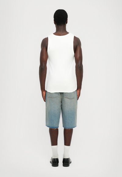 Débardeur blanc,Shorts en jean avec un ourlet effiloché, chaussures noires et chaussettes blanches. Design simple, en coton, coupe décontractée et couleur bleu clair.