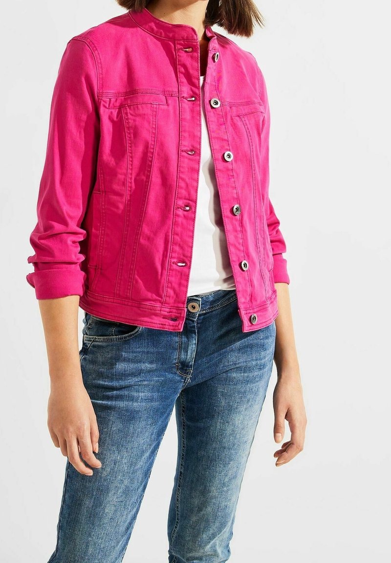 Fuchsia denim jacket with a round collar, long sleeves rolled to the elbow, front pockets, and silver buttons, worn over a white top.