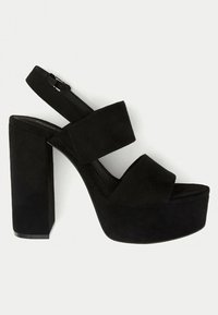 Black platform sandals with a thick block heel, made of suede, featuring two wide straps and an adjustable buckle for a secure fit.