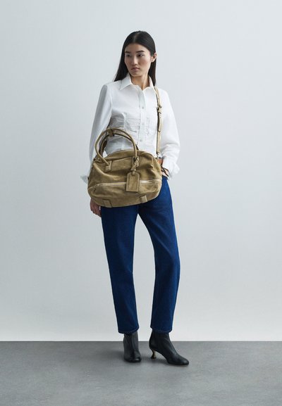 Beżowa skórzana torebka z dwiema uchwytami i odpinanym paskiem, o prostokątnym kształcie i widocznych detalach przeszycia.