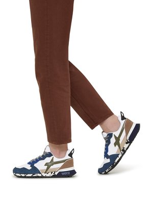 Weiße und blaue Turnschuhe mit grünen und braunen Akzenten, strukturierten Materialien, Sohlen im Camouflage-Muster und kontrastierenden Schnürsenkeln.