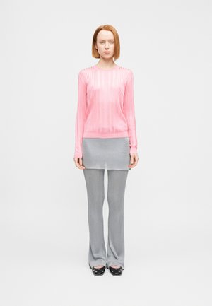 Rosa, geripptes Langarmshirt kombiniert mit einem grauen, mehrlagigen Rock und engen, grauen Schlaghosen. Die Schuhe sind schwarz mit abgerundeten Spitzen.