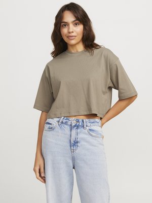 Gekürztes, kurzärmeliges T-Shirt aus olivgrünem Baumwollstoff. Kombiniert mit hoch taillierten, hellblauen Denim-Jeans im klassischen Schnitt mit ausgewaschenen Details.
