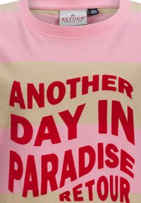 Różowa i beżowa koszulka w paski z odważnym czerwonym napisem "ANOTHER DAY IN PARADISE" oraz "RETOUR" napisanym dużymi literami. Wykonana z bawełny.