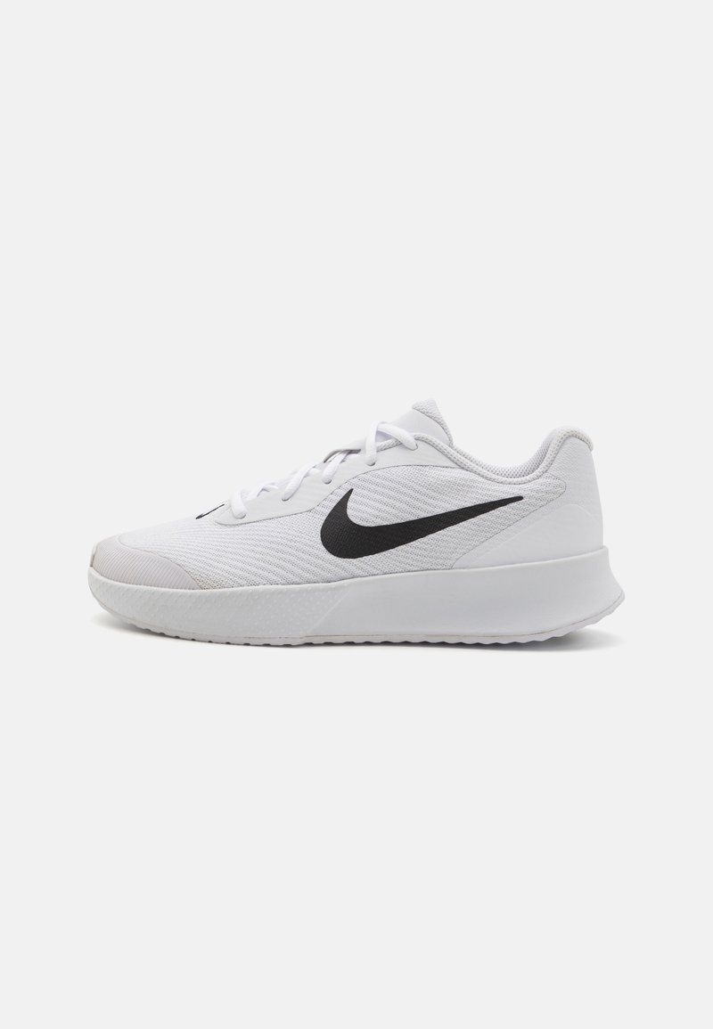 Hvit atletisk sko med en teksturert overdel i stoff, svart Swoosh-logo, snøring og en solid gummisåle med grep mønster.