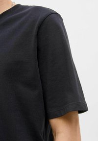 Schwarzes Baumwoll-T-Shirt mit rundem Ausschnitt und kurzen Ärmeln, das eine glatte Textur und saubere Nähte entlang der Ärmelkanten aufweist.