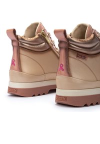 Botas de tobillo de cuero marrón claro con acentos metálicos en oro rosa, bordado con cinta rosa, detalle de cremallera y suela de goma texturizada.