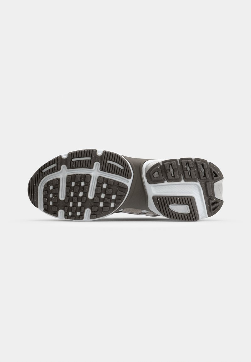 Suela de zapato con una superficie de goma negra que presenta un patrón de rejilla, acentos en gris claro y ranuras texturizadas para mayor tracción.