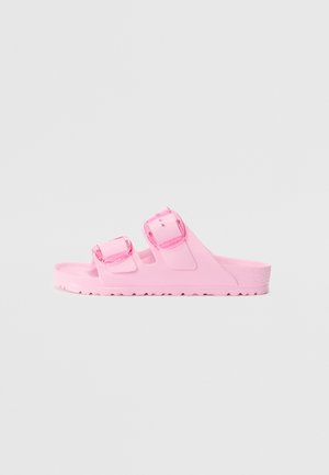 Pink slidesandal med to justerbare spænder og tekstureret sål, vist fra siden mod en ensfarvet baggrund.