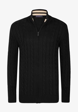 Cárdigan negro de punto con un patrón de trenzas, cuello alzado y cremallera de longitud completa. Presenta puños y dobladillo de canalé.