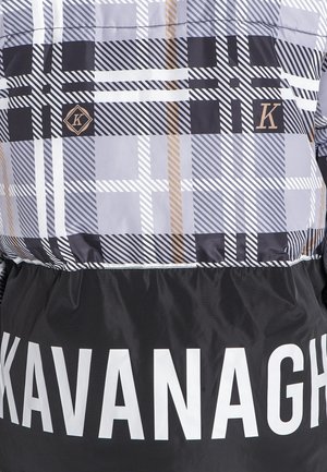 Chaqueta acolchada con un patrón de cuadros en gris, negro y blanco, con acentos dorados y una sección inferior negra con "KAVANAGH" en grandes letras blancas.