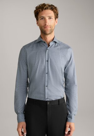 Camicia a maniche lunghe con motivo blu realizzata in tessuto leggero, presenta una chiusura con bottoni, vestibilità slim e polsini regolabili. Abbinata a pantaloni neri.