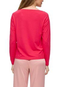 Langärmliges Shirt in leuchtendem Pink, aus weicher Baumwolle, mit rundem Halsausschnitt und lässiger Passform, kombiniert mit hellpinkfarbenen Hosen.