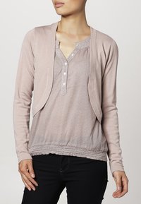 Ljust rosa långärmad topp med rundad halsringning, knapplist och strukturmönster med ett gathered nederkant. Mjuk tygfinish.