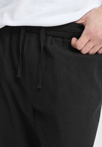 Sorte bukser med afslappet pasform lavet af tekstureret stof, med elastisk talje og snøre samt sidelommer.
