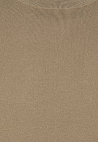 Maglione a coste beige con scollo rotondo. Il tessuto ha una leggera lucentezza, che mette in mostra una superficie morbida e testurizzata.