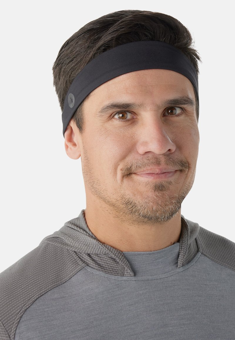 Cinta para la cabeza atlética de tela negra, usada con una camiseta de manga larga gris que presenta una capucha texturizada y acentos en los hombros.