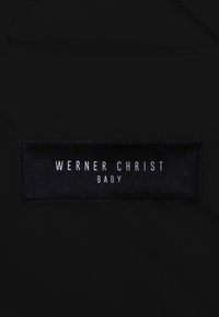 Zwarte stof met een genaaid label waarop "WERNER CHRIST" en "BABY" in witte tekst staat. Het label heeft een rechthoekige vorm met een gladde textuur.