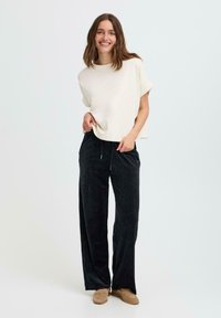 Crèmekleurig relax-fit top met korte mouwen, gecombineerd met zwarte corduroy wijde broek met een trekkoord in de taille.