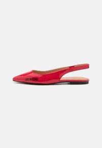 Sapatilhas slingback em verniz vermelho brilhante, com bico apontado e um pequeno logótipo preto, apresentando um calcanhar aberto e um design minimalista.
