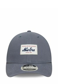 Graue verstellbare Mütze mit gebogenem Schirm. Enthält ein weißes rechteckiges Patch mit blauer Aufschrift "New Era" und "Since 1920". Hergestellt aus Stoffmaterial.