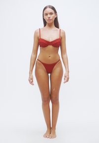 Σετ κόκκινο μπικίνι με τοπ με μπανέλα και λεπτές τιράντες, και κάτω μέρος σε χαμηλή μέση, και τα δύο από λεία, ελαστική ύφανση.