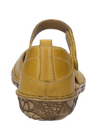 Sandal de cuero amarillo con una correa trasera, suela texturizada y patrones florales a lo largo del borde inferior. Detalle de costura en el talón.