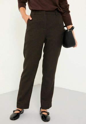 Brown textured trousers with straight legs, side pockets, and a high waistband. Paired with black patent loafers and a small black handbag.