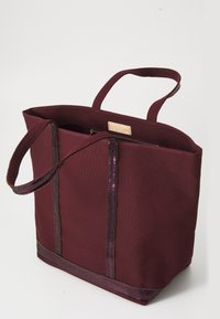 Bordeauxfarbene Tote-Tasche mit doppelten Stoffgriffen, ausgestattet mit einem Reißverschluss und Pailletten-Akzenten an den vertikalen Nähten. Langlebiges Material mit strukturierter Form.