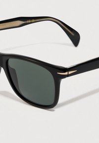 Μαύρα ορθογώνια γυαλιά ηλίου με σκούρους πράσινους φακούς και χρυσή λεπτομέρεια στον βραχίονα του σκελετού, παρουσιασμένα σε λευκό φόντο.