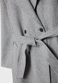 Manteau en laine gris clair avec boutons noirs et ceinture en tissu nouée à la taille, doté d'un col cranté et de poches latérales.