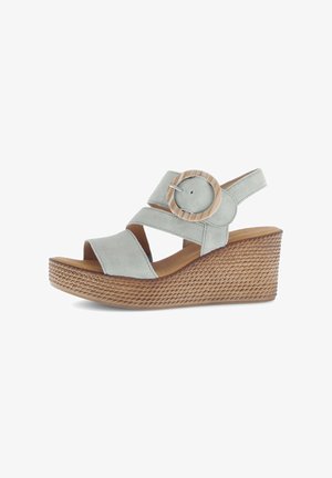 Light gray suede wedge sandals with a woven texture. Features cross straps and a large wooden circular accent on the side.