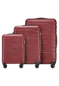Trois valises rigides rouges assorties de tailles variées, avec des surfaces texturées, des roues noires et des zips, affichant un design élégant.