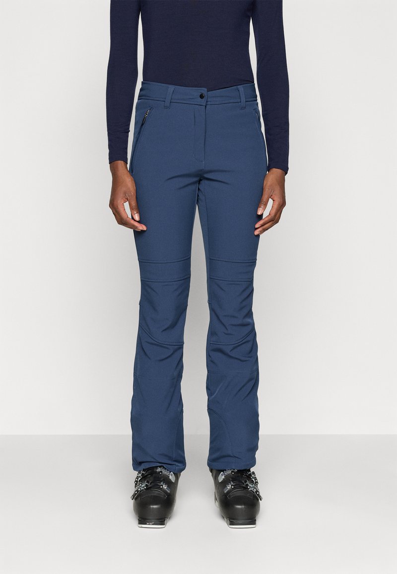 Mørkeblå skibukser med slim fit, med en glidelås lomme, buede sømmer og et behagelig stretchy stoff. Brukt med svarte skistøvler.