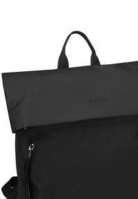 Černý látkový batoh s rolovacím designem, vybavený polstrovanou rukojetí a uzávěrem na zip. Povrch je hladký s jemným vzorem.