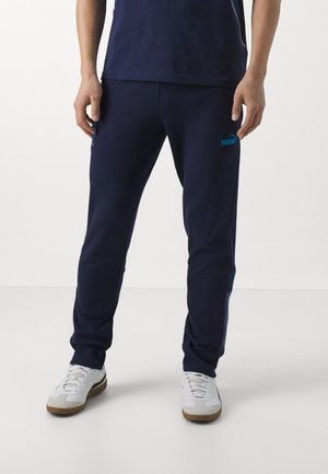 Pantalons de jogging bleu marine en tissu doux, dotés d'un design slim, avec un logo Puma turquoise sur la jambe gauche et des poches latérales.