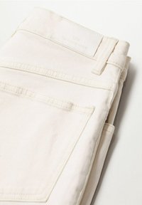 Valkoiset denimpöksyt, joissa sileä tekstuuri, ommellut taskut, yksinkertainen vyötärönauha ja kangasmerkki, jossa lukee "Authentic Denim".