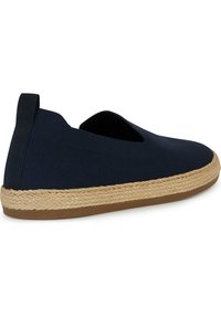 Zapato tipo slip-on en color azul marino con un upper de tela texturizada y apertura elástica. Presenta una suela envuelta en yute y un fondo de goma marrón.