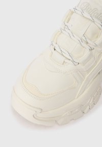 Puspārliecinošas baltas sporta kurpes ar gludu ādas virsu, teksturētu gumijas zoli un izteiksmīgu auklu sistēmu. Iekļauj diskrētu zīmola emblēmu un izšūtu akcentu.