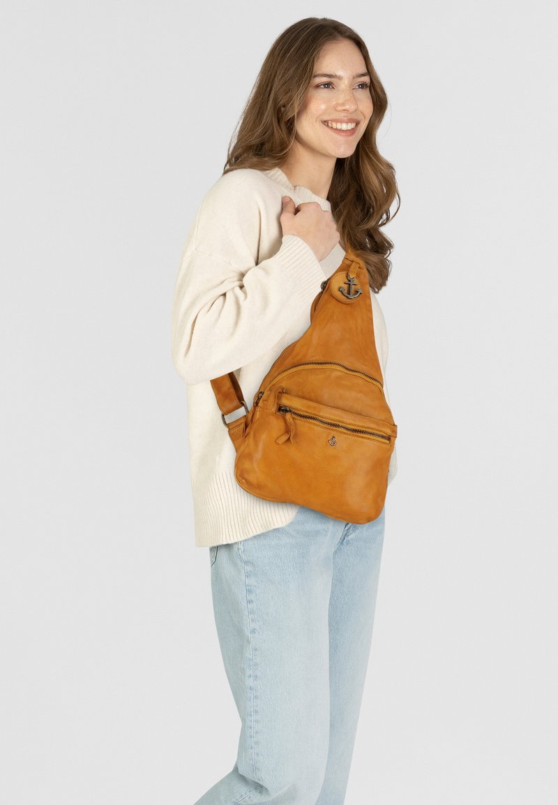 Oranje leren schoudertas met twee ritszakken, verstelbare schouderband en ankerlogo-detail. Effen textuur en minimalistisch ontwerp.