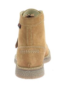 Stivale alla caviglia in suede marrone con punta arrotondata, dettagli cuciti e suola in gomma testurizzata. Presenta un'etichetta sul retro per una facile vestibilità.