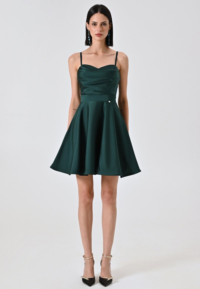 Robe en satin verte avec un corsage ajusté, décolleté en cœur et jupe évasée. Dispose de fines bretelles et d'un petit accent métallique.