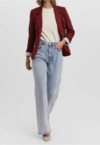 Burgundipukuisu vaate kremiä topin päällä, yhdistettynä vaaleansinisiin leveälahkeisiin farkkuihin. Asusteessa on puhdas muotoilu, rento istuvuus ja hienovaraisia tekstuureja.